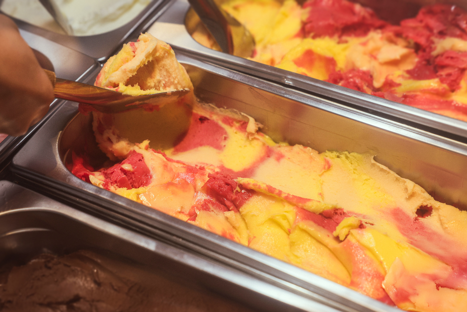 스테인리스 트레이에서 빨강·노랑 아이스크림을 떠 담는 쇠맛 아이스크림 제작 과정